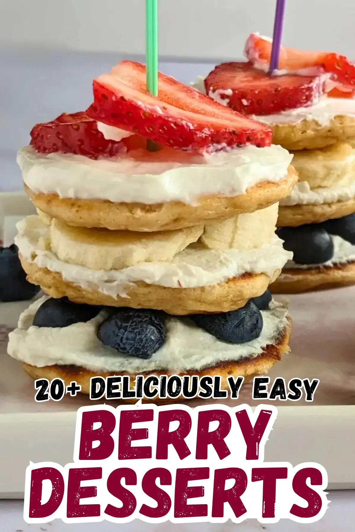 Pancake Stacks With Fresh Blueberries and Strawberries - small pancakes spread with sweet ricotta and layered in a stack with blueberries in the bottom layer, banana slices in the middle, and strawberries at the top, secured with toothpicks.